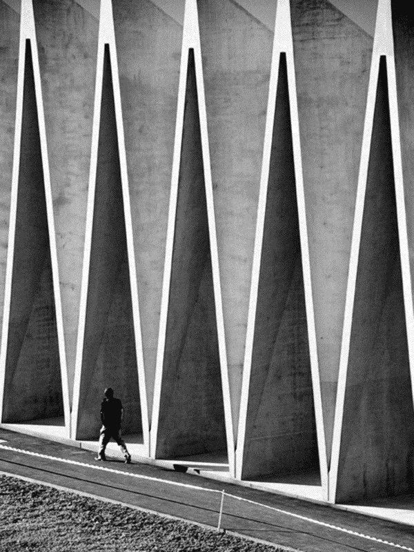Man walks beneath a concrete architectural structure for Other e-reader wallpaper or screensaver featuring architecture and concrete and more